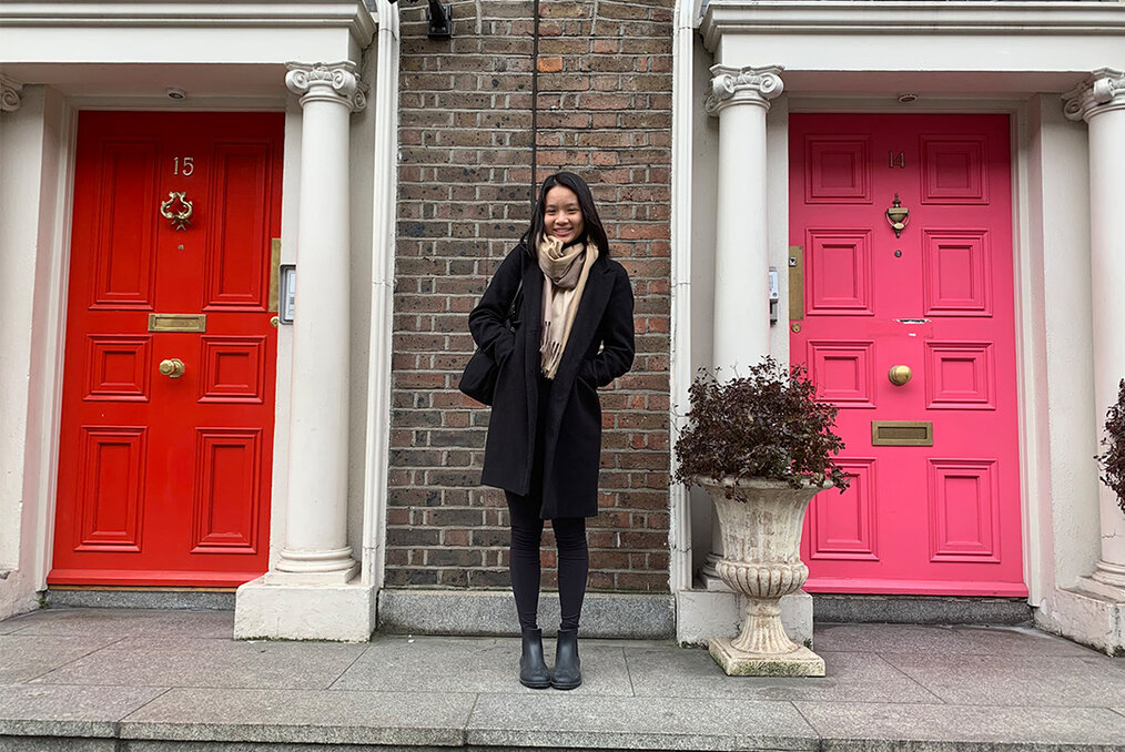 A person standing in front of two residential doors, one red and one pink
